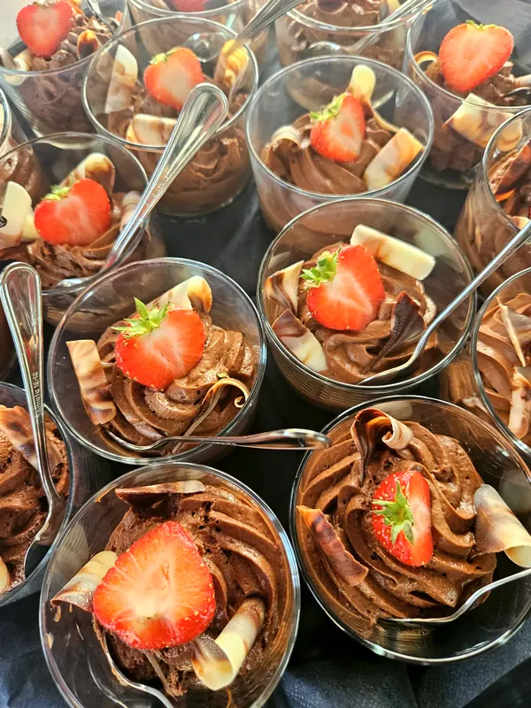 Chocolademousse in glaasjes met een halve aardbei en krullen van chocolade.