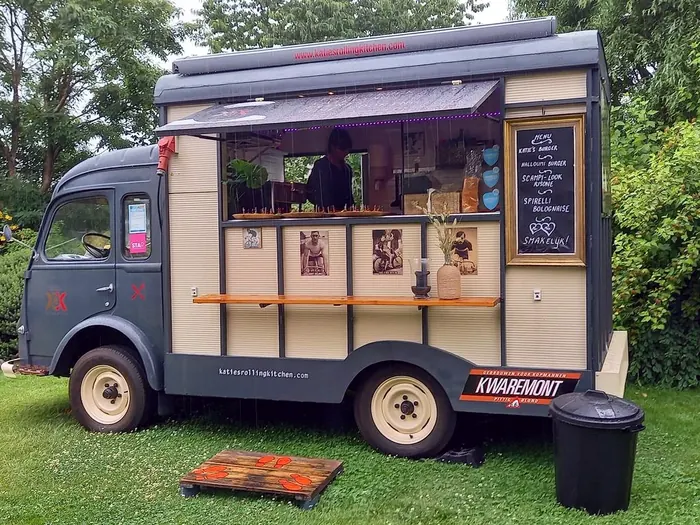 De Goelette aan het werk: luik open, hapjes op de toog, oude wielerfoto's op de panelen en een krijtbord met Katie's burger, halloumiburger, scampi-look risone en spirelli bolognaise.