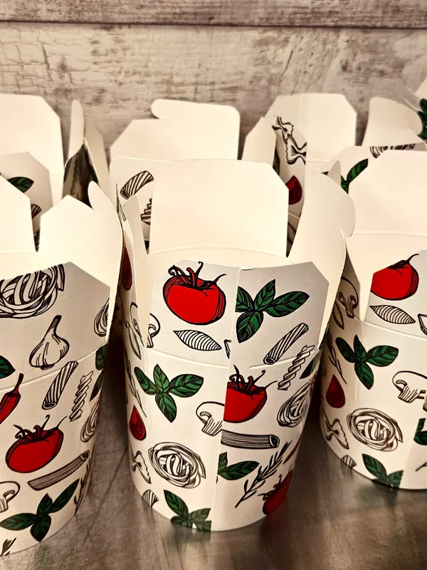 Een rij lege pastabekers van karton, bedrukt met tomaten, basilicum, look en pasta.